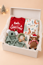 Load image into Gallery viewer, Babynor baby’s first Christmas gift box with red bodysuit, woodland swaddle, sage koala comforter, crochet reindeer and emerald dummy clip
