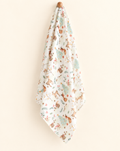 Load image into Gallery viewer, Woodland Christmas bamboo and organic cotton muslin swaddle hanging against a warm ivory background
